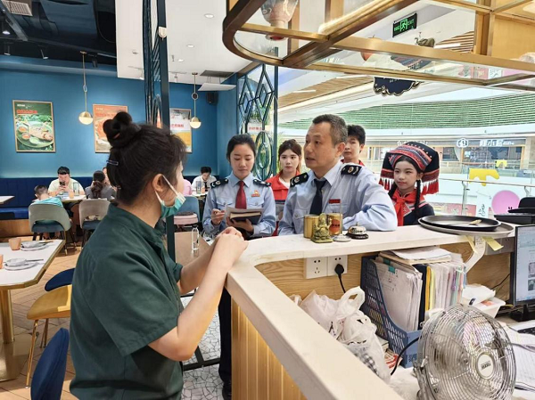 志愿者跟随税务工作人员走访商铺开展税法普及与政策宣传